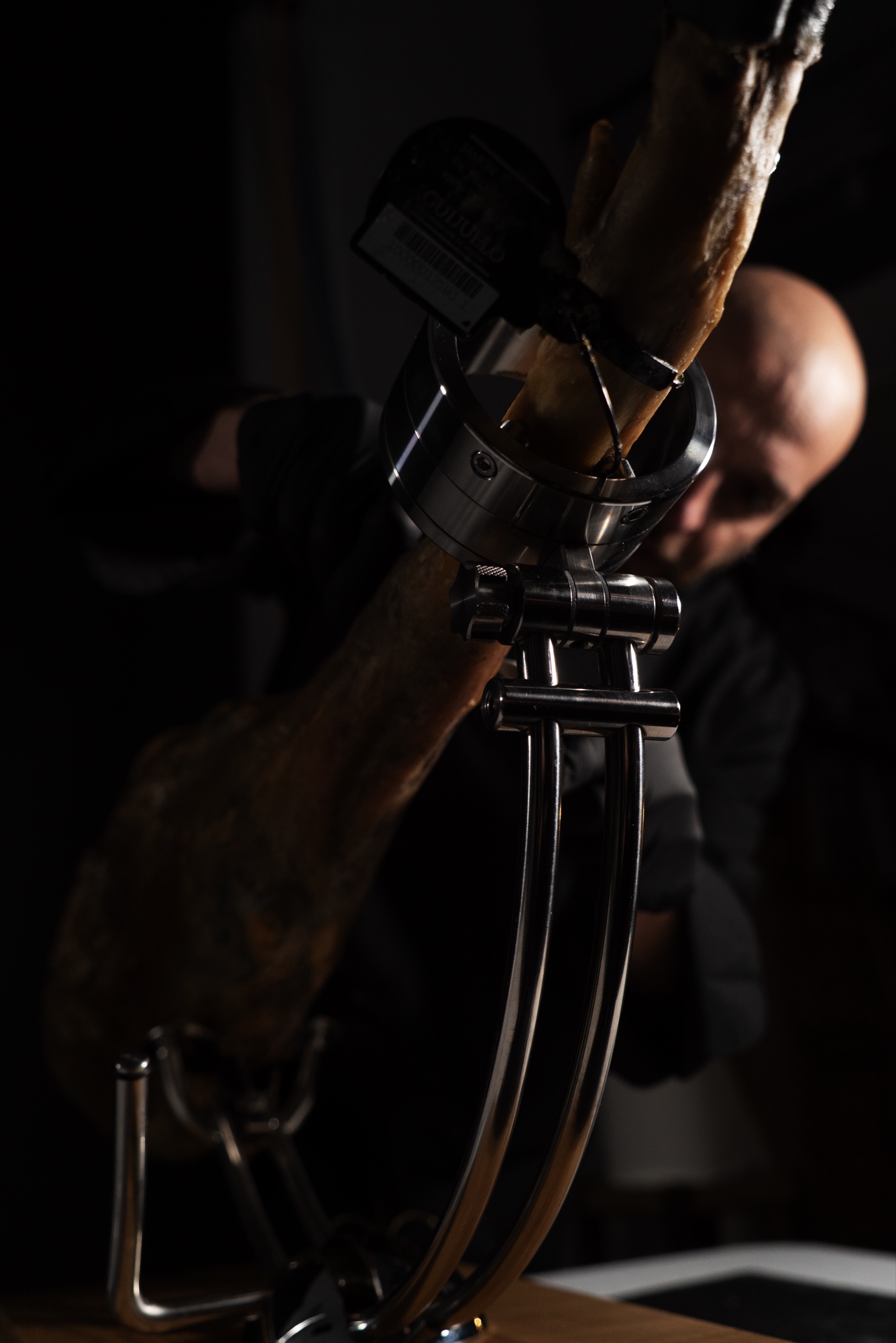 Detalle del jamonero con Antonio Muti desenfocado al fondo